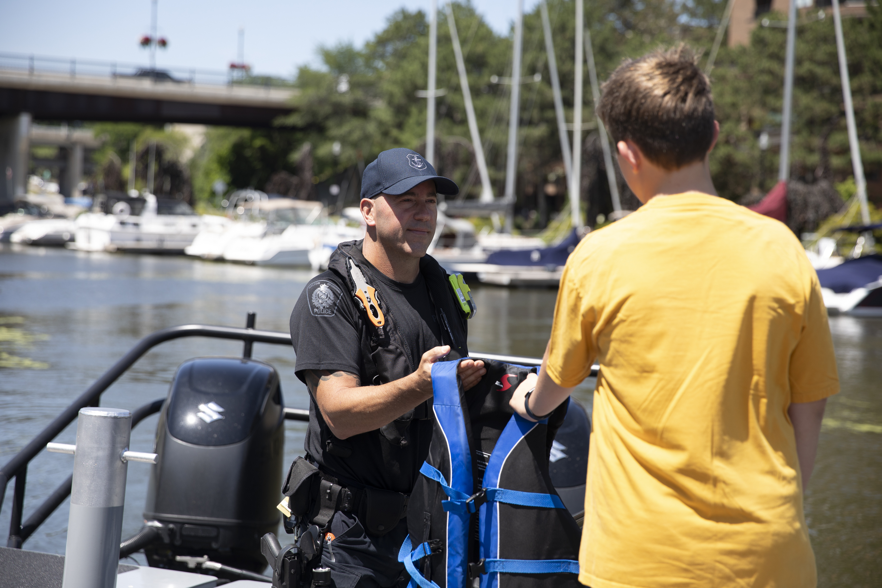 Officer handing a youth a life jacket before boarding a boat